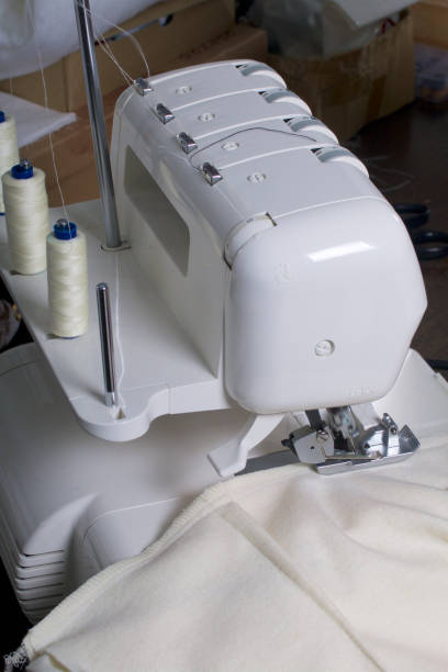 istock Product processing on overlock. Overlock with installed white threads and fabric clamped in the clamp of the overlock. 880454834