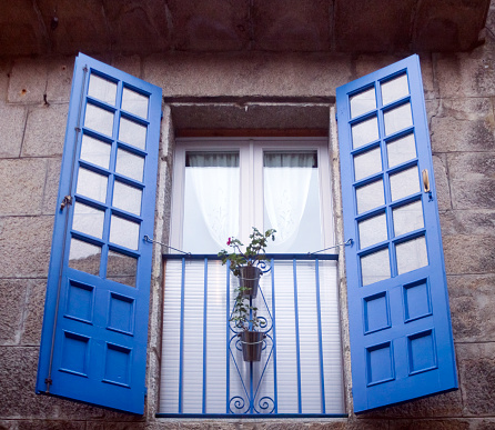 Beautiful blue shutters. Restored window on old stone facade.