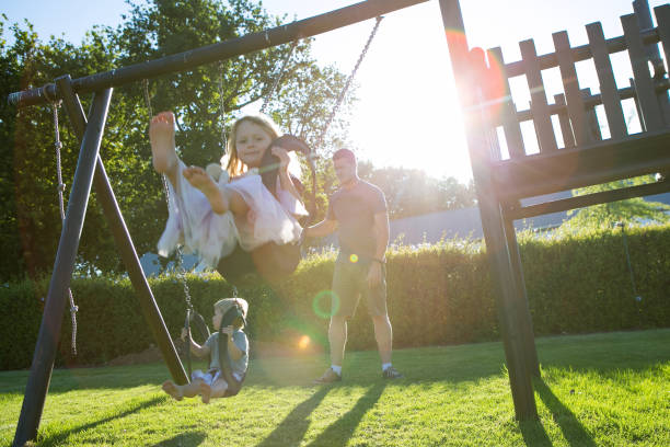 istock Father and his two children playing on the swing 880494632