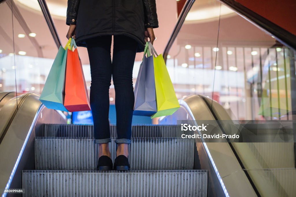 Jambes de femme avec des sacs à provisions colorés sur l’escalator dans un centre commercial - Photo de Centre commercial libre de droits