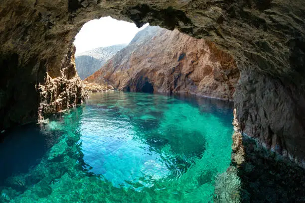 Photo of Natural rocky arch with clear transparent waters, in Tragonissi islet, Myconos, Greece