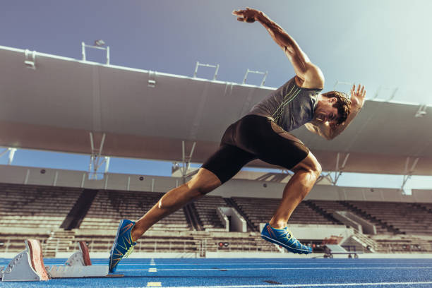 sprinter despegar del bloque que comienza en la pista de atletismo - pista de atletismo de tartán fotografías e imágenes de stock