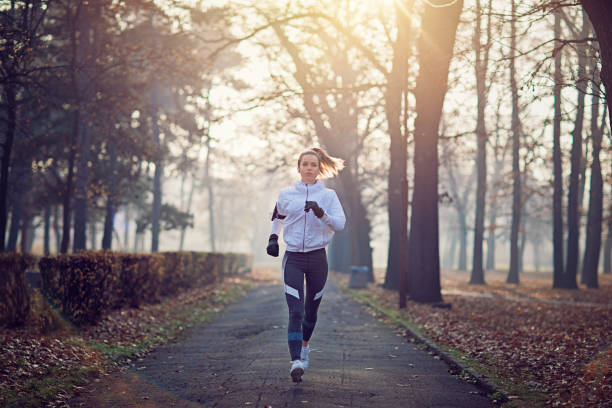 Young woman is running in the cold foggy morning stock photo