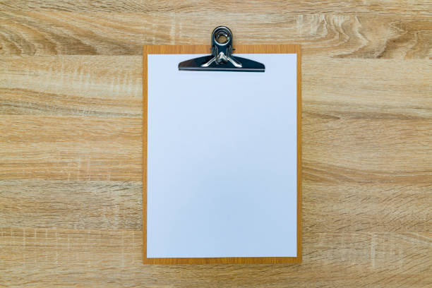 istock clipboard with blank white paper sheet on wood table top view with copy space. 880620314