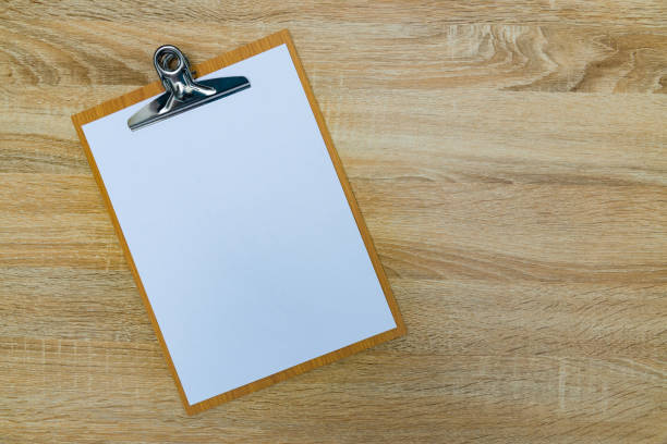 istock clipboard with blank white paper sheet on wood table top view with copy space. 880620316