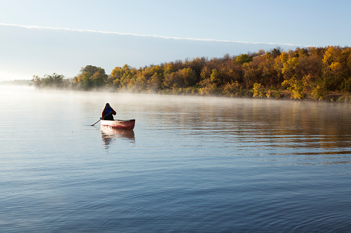Scenic foggy morning, woman canoeing at Buffalo Pound Provincial Park. Image taken from a tripod.