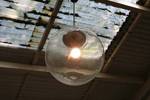 Light bulbs hanging from old acrylic transparent roof.