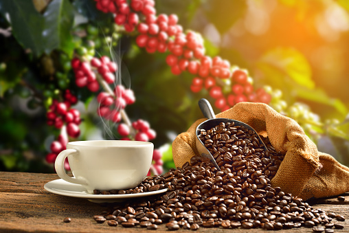 Cup of coffee with smoke and coffee beans on old wooden background