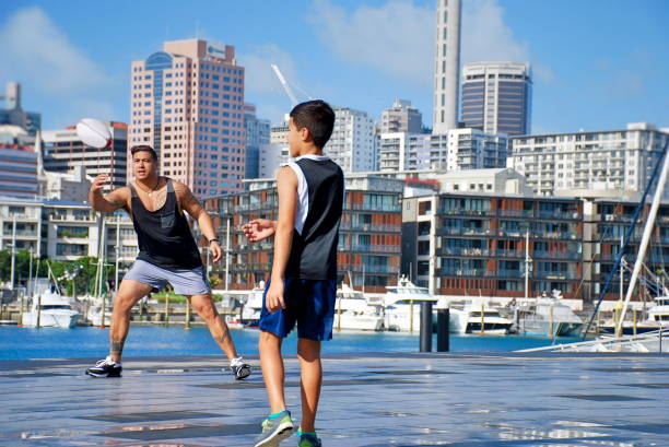 Pacific Islander Father and Son Playing Ball in Urban Cityscape Scene A Pacific Islander Father and Son in Casual Sports Clothing Playing Ball in Urban Cityscape Scene. This Image is taken at the Viaduct Harbour in Auckland's Downtown Area. Waitemata Harbor stock pictures, royalty-free photos & images