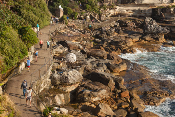 Sculpture by the Sea park Bondi, Australia - November 2015: People enjoying a morning walk or job through the Sculpture by the Sea public park by Bondi beach. bondi beach sunrise stock pictures, royalty-free photos & images