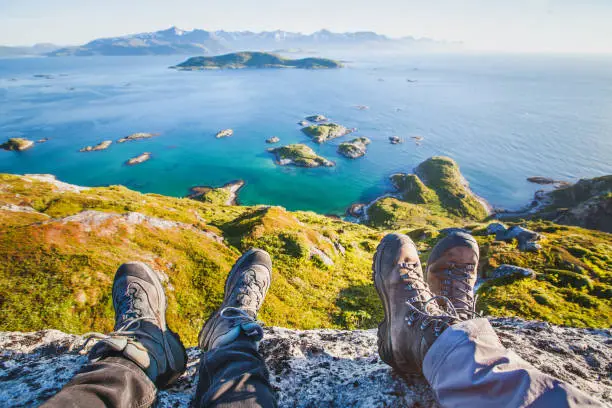feet of people hikers relaxing on top of the mountain, travel background, hiking shoes