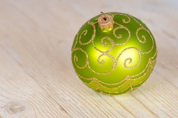 green christmas bauble on white wooden table
