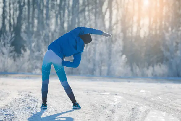 Photo of Runner stretching in winter Park. A healthy way of life.