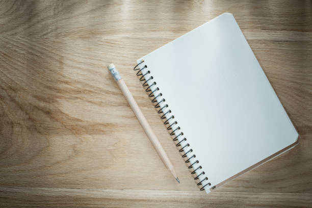 istock Opened copybook pencil on wooden board 880795334