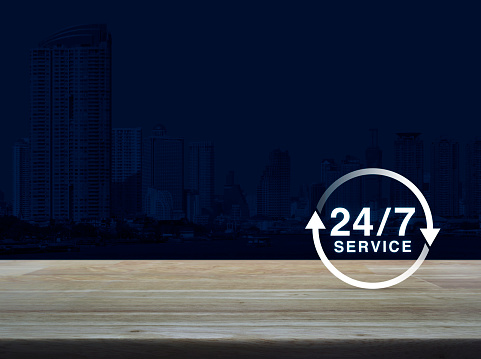 24 hours service icon on wooden table over modern office city tower background, Full time service concept