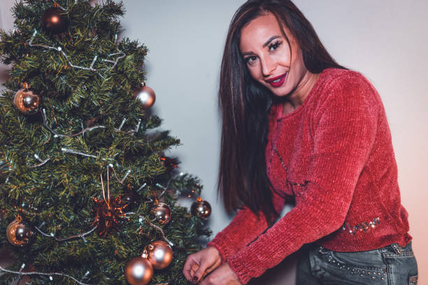 istock Beautiful young woman decorating christmas tree at home 880801476
