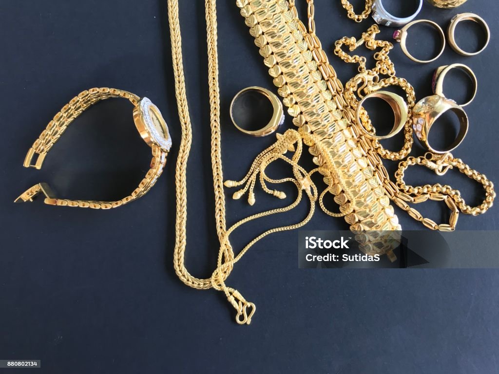 Gold jewelry for personal accessories Pile of golden necklace, bracelet and rings on black background Jewelry Stock Photo