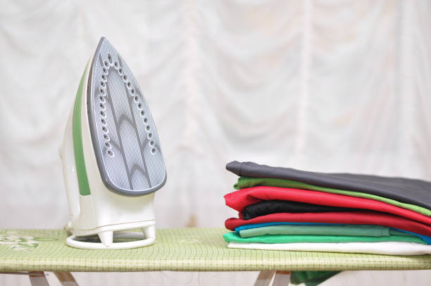 istock Iron and clothes on ironing board. 880804450