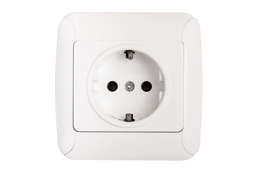 White double outlet installed on white wall with inserted black electrical plug, front view.