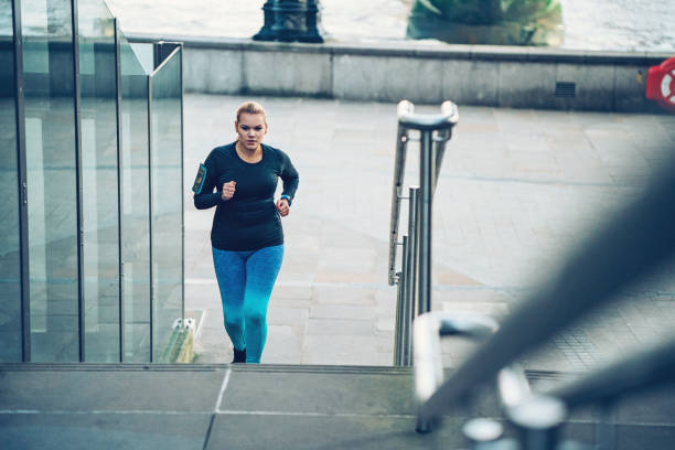 jóvenes con sobrepeso a mujer que corre al aire libre en la ciudad - staircase running moving up jogging fotografías e imágenes de stock