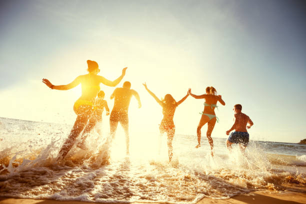 grande gruppo amici tramonto mare spiaggia corsa - beautiful caucasian teenager running foto e immagini stock