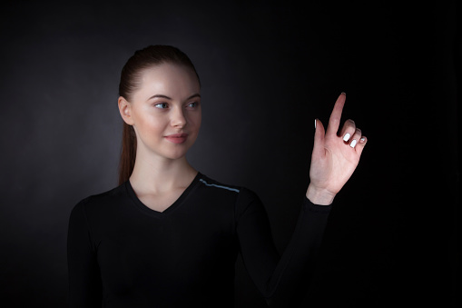 Young woman pointing with finger at virtual display