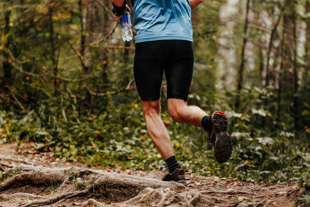istock man runner water bottle in hand running on forest trial 880842216