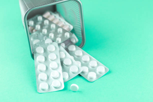 istock Trash bin with packs of white capsules and pills packed in blisters with copy space on aquamarine background. Focus on foreground, soft bokeh 880845468