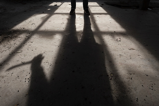 A man walks through a vast dark space towards a brightly-lit a doorway (miniature photography).