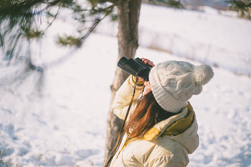 girl looking through binoculars and mountainscape