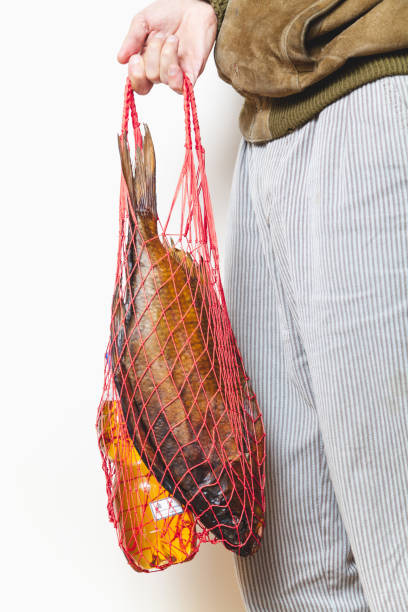 魚とビールのネットを保持しているストライプのパンツの男 - red band bream ストックフォトと画像