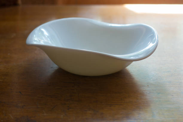 istock Asymmetric white porcelain bowl on wooden table 880864346