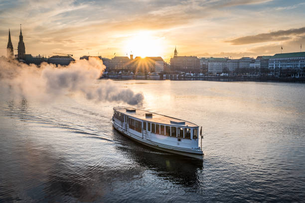 bateau à vapeur sur le lac alster à hambourg avec cityscape en arrière-plan pendant le coucher du soleil - passenger ship flash photos et images de collection