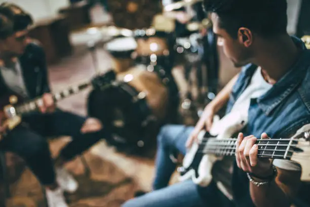 Repetition of rock music band. Bass guitar player, electro guitar player and drummer behind the drum set. Rehearsal base