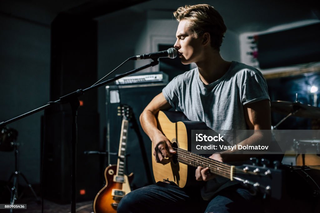 Lyric singer with acoustic guitar. Handsome young man on rehearsal base. Lyric singer with acoustic guitar. Singer Stock Photo