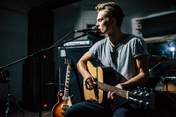 Lyric singer with acoustic guitar. Handsome young man on rehearsal base. Lyric singer with acoustic guitar. rhythm photos stock pictures, royalty-free photos & images