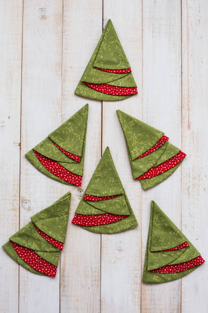 patchwork and quilting concept - macro of colorful decorative red-and-green napkins on a whitewashed wooden floor, festive embroidered towels in shape of christmas trees, top view, flat lay, vertical - christmas quilt craft patchwork imagens e fotografias de stock