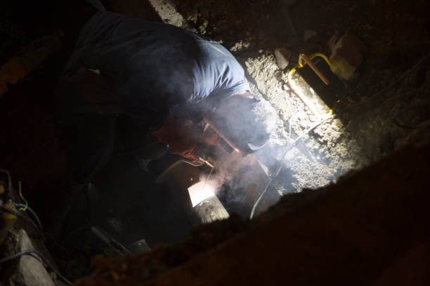 istock Manual metal arc welding pipeline in a trench at night 880914464