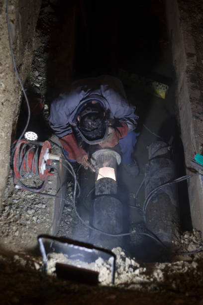 istock Manual metal arc welding pipeline in a trench at night 880914512