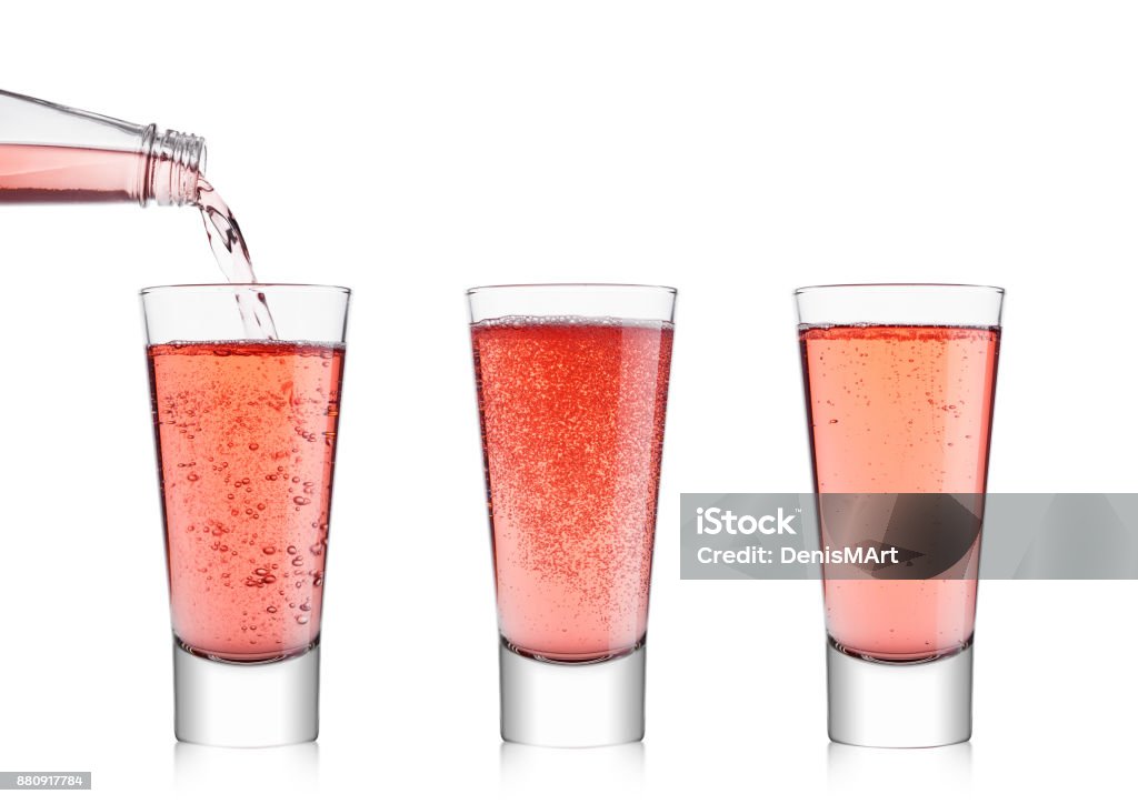 Pouring pink soda lemonade from bottle to glass Pouring pink soda lemonade from bottle to glass on white background Carbonated Stock Photo