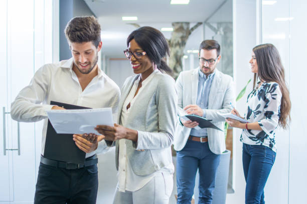 istock Business people discussing over documents in office lobby. 880917800