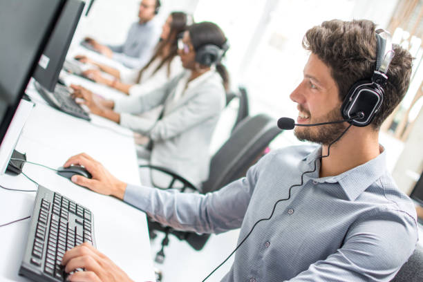 istock Smiling handsome male customer support phone operator with headset working in call centre. 880918576