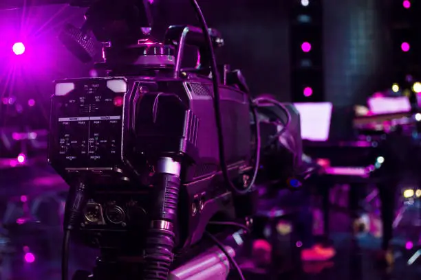 Photo of professional digital video camera in a concert hall and blur piano background
