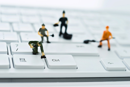 A group of figurines cleaning computer keyboard