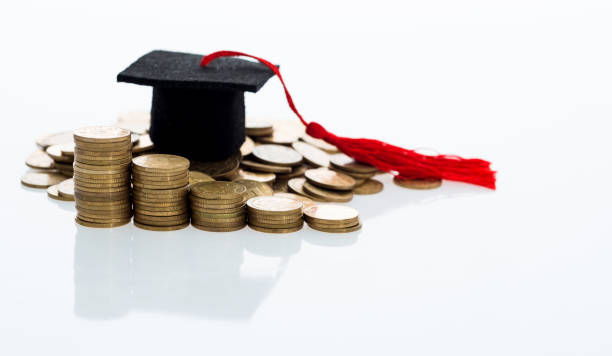 istock Graduation hat and heap of coins 880924702