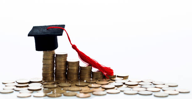 istock Graduation hat and heap of coins 880924754