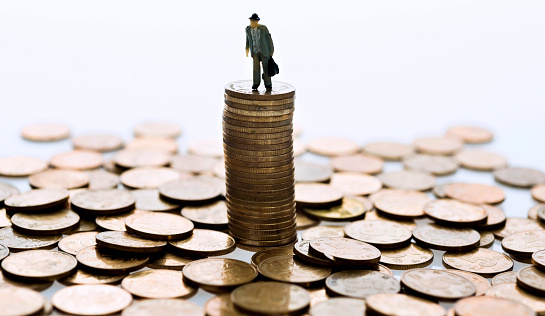 Man figurine standing on stack of coins
