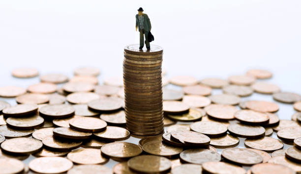 Man figurine standing on stack of coins Man figurine standing on stack of coins top gold ira stock pictures, royalty-free photos & images