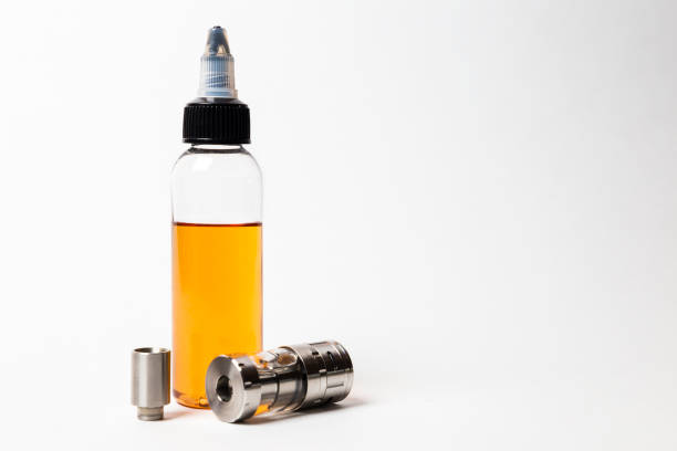 istock e- liquid, e-juice in the bottles and vaping devices isolated on the white background with copyspace 880949978