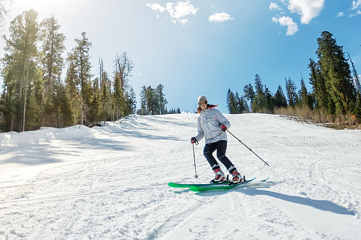 Young girl on alpine skiing on a snowy track against the sky.